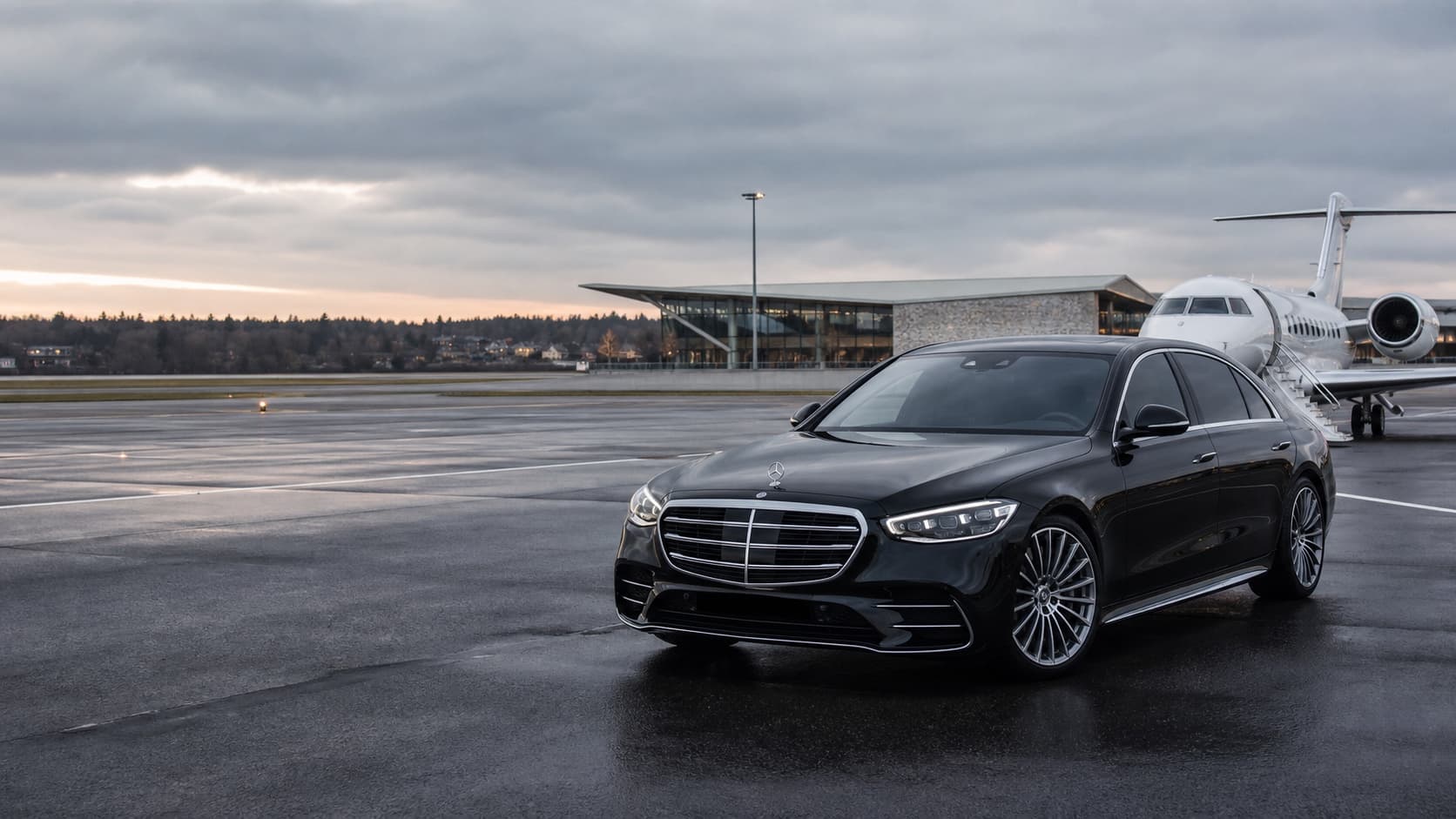 A black Mercedes-Benz sedan meeting a private aircraft at a Stockholm airport